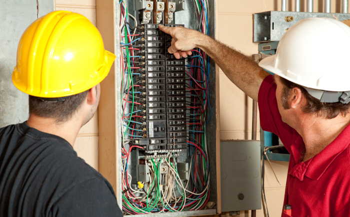 Tw.o electricans working on an electrical panel repair