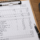 Electrical load calculation form on a clipboard with a calculator and pen.